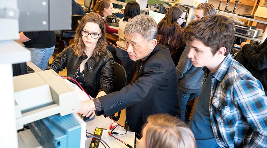 students working in the lab and a professor helping a group